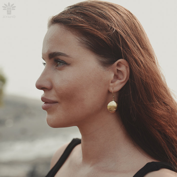 Circular bronze hoops with dangling mirror charms, styled with a linen dress for boho festival vibes