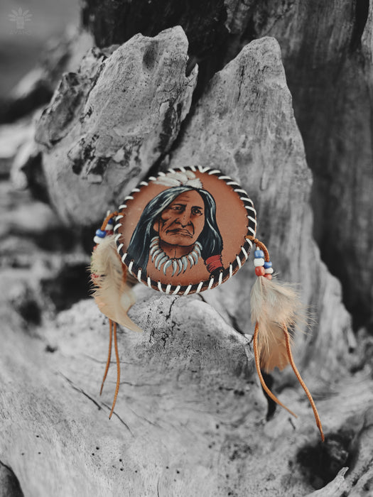 Artisan-crafted feather brooch with turquoise beads and suede ties, displayed on a woven tapestry for earthy vibes.