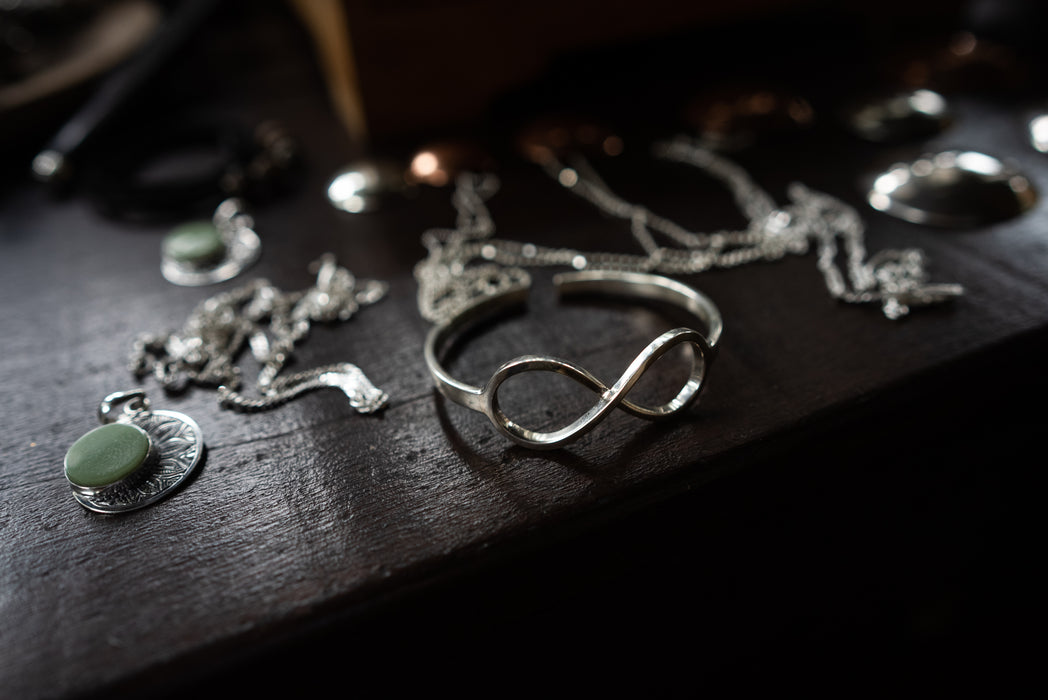 Silver jewelry with green stones on a dark wooden surface