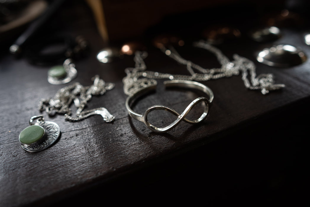 Silver jewelry with green stones on a dark wooden surface