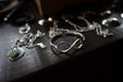 Silver jewelry with green stones on a dark wooden surface