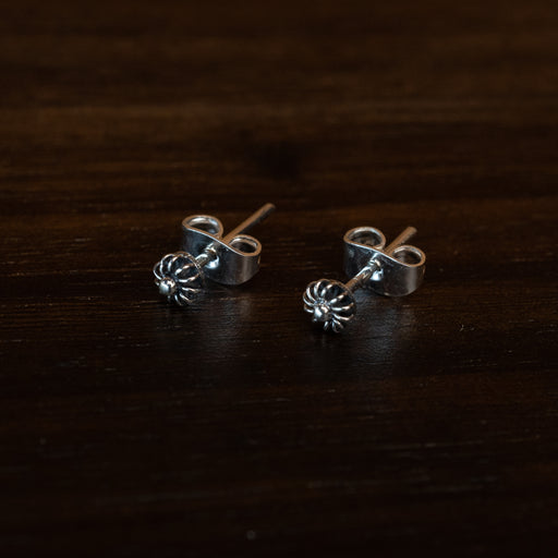 Close-up of hand-engraved floral stud earrings with cubic zirconia centers, displayed on a rustic wooden tray with dried lavender for boho charm.