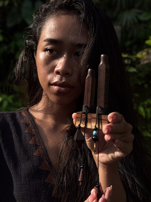 Person holding a set of wooden tuning forks against a dark background