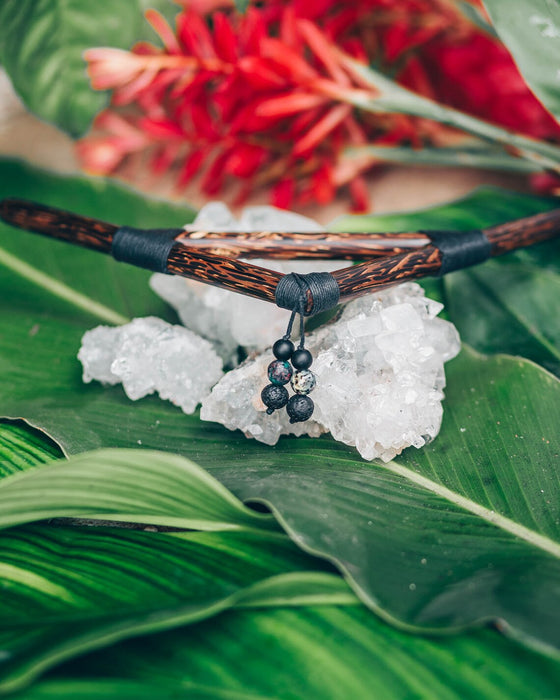 Necklace with wooden and black elements on a crystal and leaf background