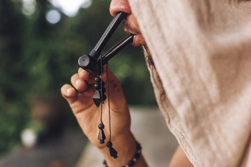 Person holding a black folding knife with a blurred natural background