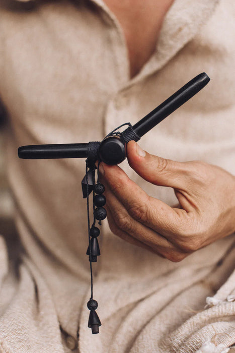 Person holding a black hair straightener with a blurred beige background