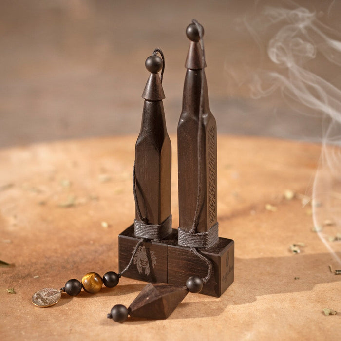 Wooden incense holders with smoke on a sandy background