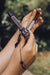 Hand holding a decorative knife with a blurred natural background
