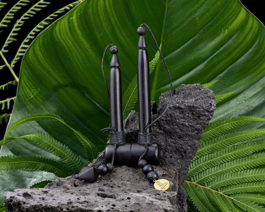 Black metal sculpture on a rock with green leaves in the background
