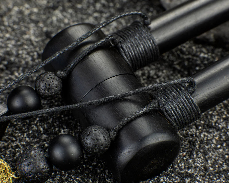 Black earbud with woven cord on a textured surface