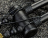 Black earbud with woven cord on a textured surface