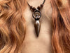 Necklace with a unique pendant worn by a person with red hair