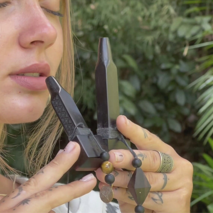Person holding a black geometric object close to their face with a blurred green background