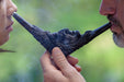 Two people sharing a large decorative smoking pipe against a blurred green background