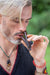 Man smoking a pipe outdoors with a blurred green background