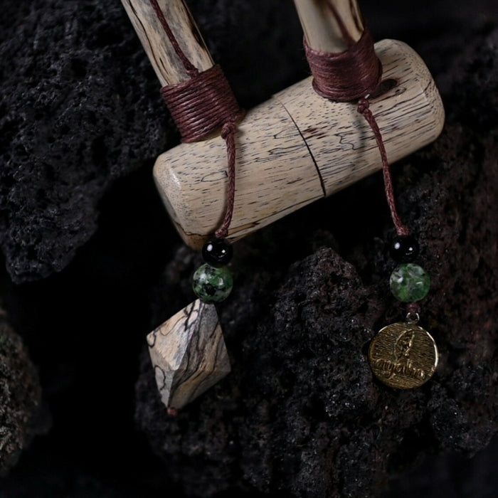 Wooden pendant with beads and a coin on a dark textured background