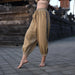 Person wearing beige traditional pants with a decorative stripe in front of a temple.