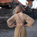 Woman in a beige outfit standing in front of traditional architecture