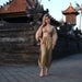 Woman in a beige outfit standing in front of traditional architecture