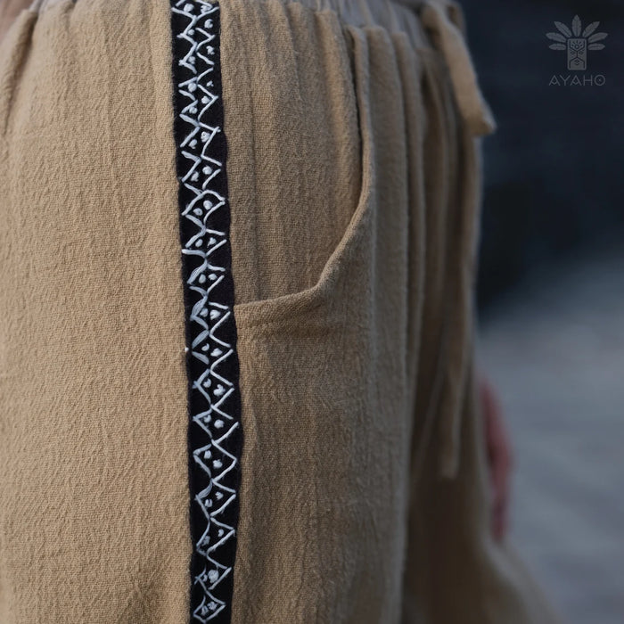 Close-up of a beige garment with a black and white patterned trim, featuring the AYANO brand logo.
