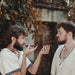 Two men in historical attire interacting with a small object outdoors.