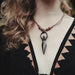 Necklace with a unique pendant worn by a person with wavy hair.