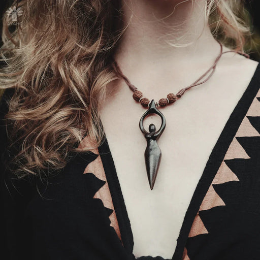 Necklace with a unique pendant worn by a person with wavy hair.