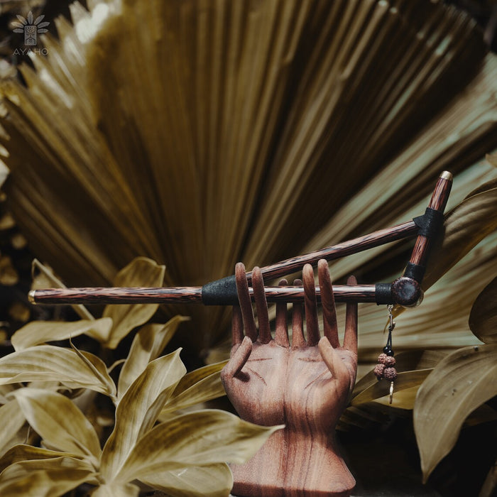 Wooden hand holding a stick with leaves in the background