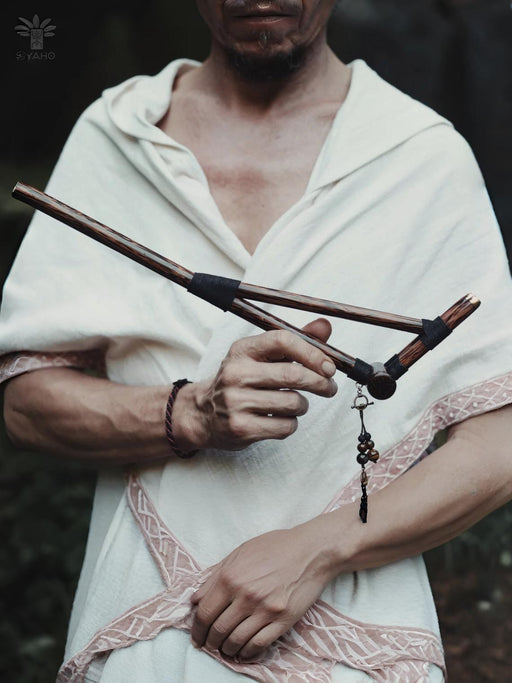 Person holding a wooden staff with a dark background