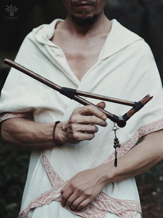 Person holding a wooden staff with a dark background