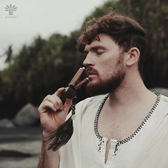 Man holding a feathered pipe with a natural background