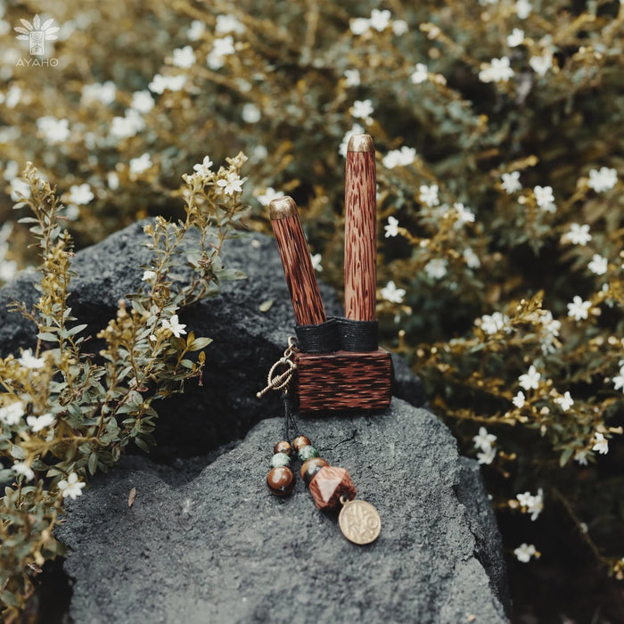 Small wooden mallet with decorative elements on a rock surrounded by greenery