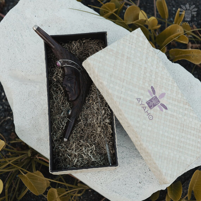 Wooden smoking accessory in a box with Ayaho branding on a textured surface.