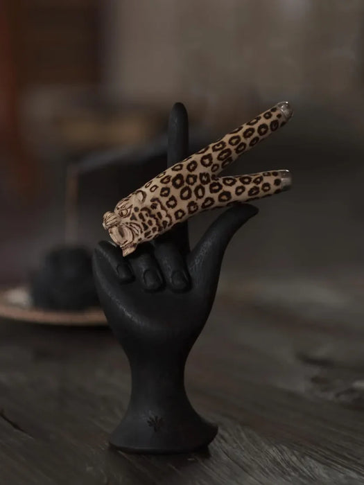 Leopard print hair clips on a black hand-shaped stand with a blurred background