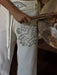 Person wearing white pants with black abstract designs, holding a wooden object.