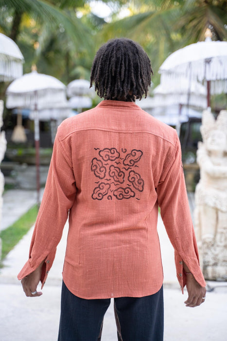 Person wearing a pink shirt with a black design outdoors