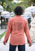 Person wearing a pink shirt with a black design outdoors