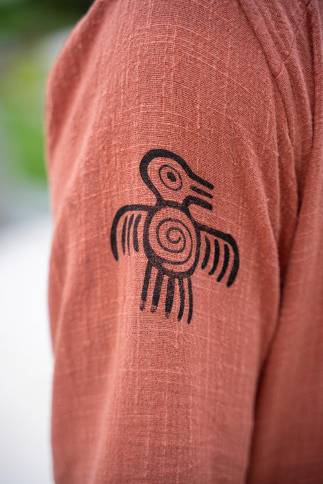 Brown fabric with a black bird-like symbol on a blurred natural background