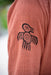 Brown fabric with a black bird-like symbol on a blurred natural background