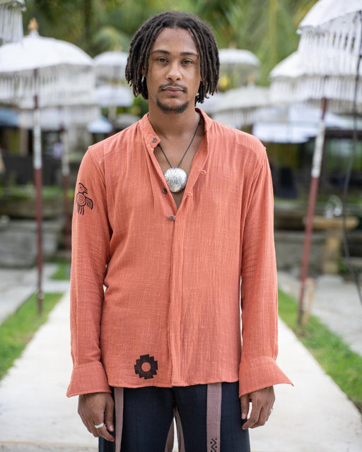 Man wearing an orange shirt with a tropical setting in the background
