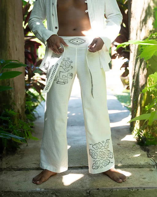 Person wearing white pants with embroidery in a natural setting
