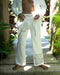 Person wearing white pants with embroidery in a natural setting