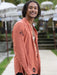 Man wearing a peach-colored shirt with patterns, standing outdoors.