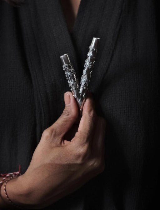 Hand holding a silver object against a dark background