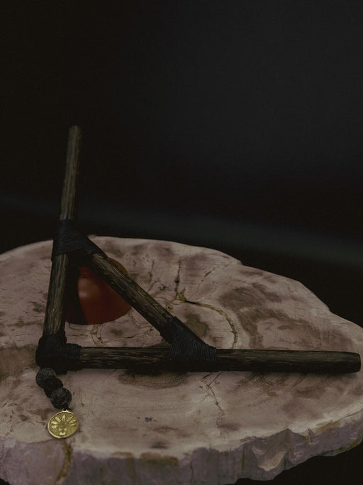 Wooden triangle with a string and small round object on a textured surface