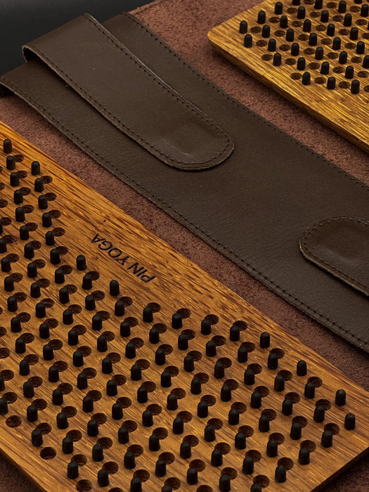 Wooden tool with textured surface and brown leather strap, featuring 'PIN YOGA' branding.