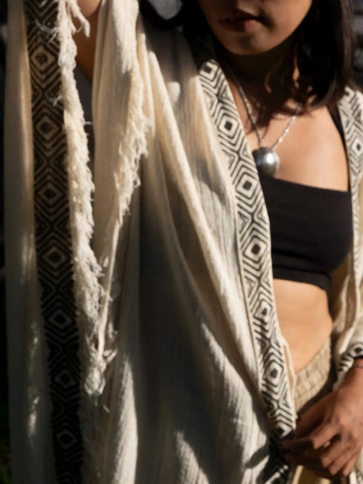 Person wearing a black top and beige shawl with geometric patterns.