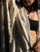 Person wearing a black top and beige shawl with geometric patterns.