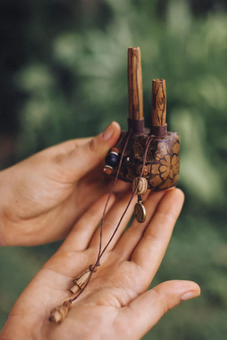Hand holding a small decorative item with a blurred green background