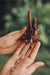 Hand holding a small decorative item with a blurred green background